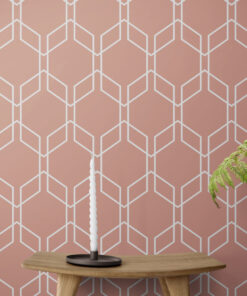 Pink hexagon geometric wallpaper on wall behind candle sitting on a wooden stool
