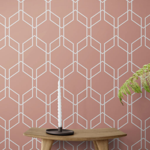 Pink hexagon geometric wallpaper on wall behind candle sitting on a wooden stool